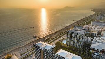 Un paysage urbain côtier avec un bâtiment imposant doté d’une piscine sur le toit et offrant une vue sur la plage et l’océan.