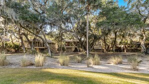 A coastal property with multiple wooden cabins surrounded by mature trees and sand dunes. - Charming Island Getaway with a Furnished Deck Offering Forest & Fairway Views (Seabrook Island)
