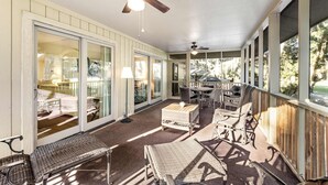 A covered porch with wicker furniture, a ceiling fan, and large sliding glass doors leading to an outdoor area. - Charming Island Getaway with a Furnished Deck Offering Forest & Fairway Views (Seabrook Island)