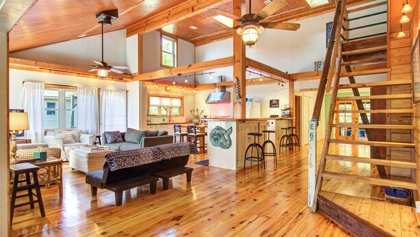 A spacious living area with a wooden floor, a sofa, a coffee table, and a staircase.