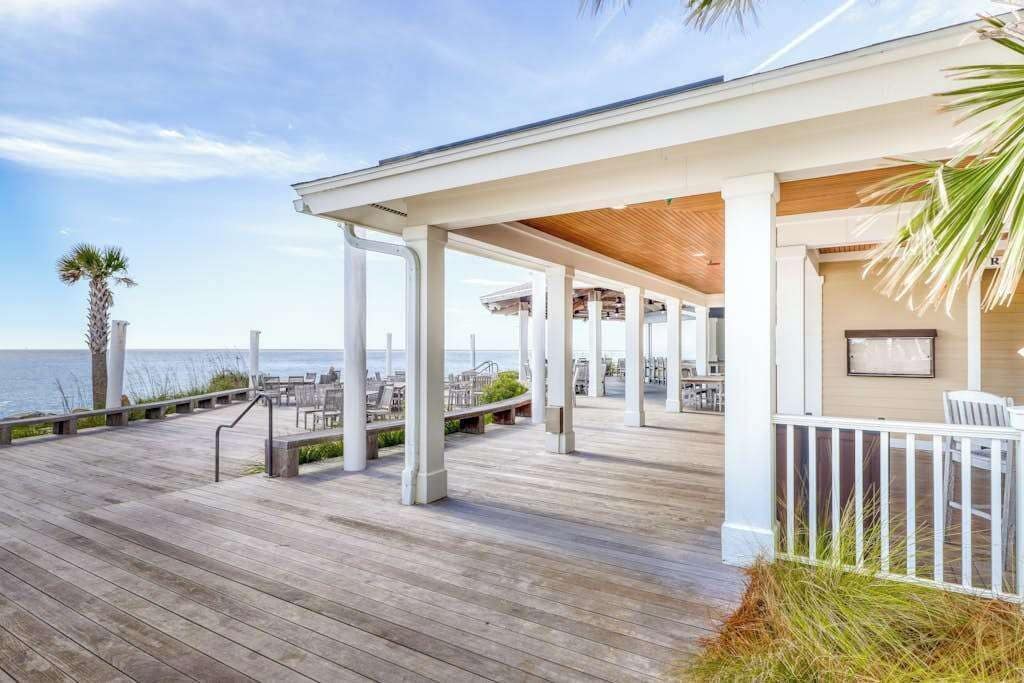 A wooden deck with white railings and a view of the ocean.