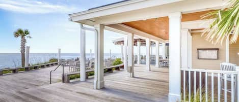 A wooden deck with white railings and a view of the ocean.