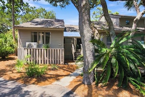 A residential property with a detached house, a covered porch, and a well-maintained garden with palm trees.