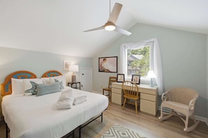 A bedroom with a bed, desk, chair, and a ceiling fan.