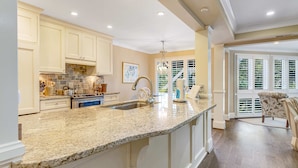 A spacious kitchen with granite countertops, white cabinetry, and a large island.