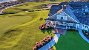 A coastal property with a large house, a well-maintained lawn, and a golf course.
