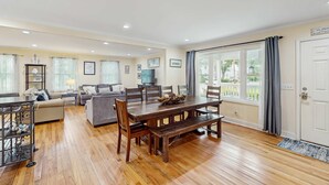 A spacious living room with a wooden dining table, sofas, and a TV.