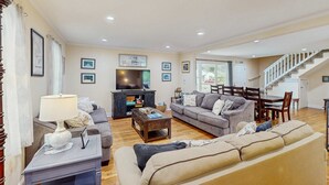 A spacious living room with a fireplace, sofas, a coffee table, and a staircase leading to another level.