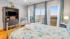 Une chambre à coucher avec un lit, une télévision, une commode et un balcon offrant une vue.