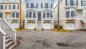 Une rangée de maisons de ville avec une entrée centrale, plusieurs garages et une allée gravillonnée.