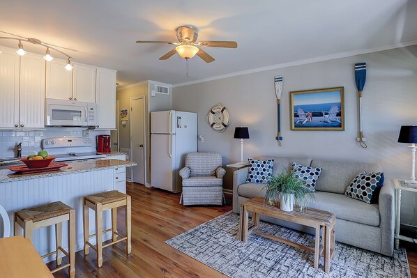 A compact living space with a kitchenette, a dining area, and a seating area with a sofa and a chair.