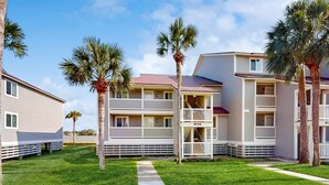 A beachfront hotel with multiple-story buildings, balconies, and palm trees. - Elegant riverfront condo with access to private W/D, central AC, and pool access (Folly Beach)