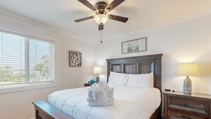 A bedroom with a bed, a nightstand, a lamp, a ceiling fan, and a window with blinds. - Elegant riverfront condo with access to private W/D, central AC, and pool access (Folly Beach)
