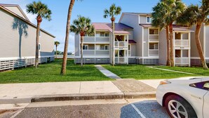 A beachfront hotel with multiple-story buildings, balconies, and palm trees. - Elegant riverfront condo with access to private W/D, central AC, and pool access (Folly Beach)