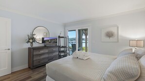A bedroom with a bed, a dresser, a mirror, a television, and a window with a view of the outdoors. - First-floor villa w/ magnificent river view & community pool/dock/tennis courts (Folly Beach)