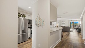 A modern kitchen with stainless steel appliances, a central island, and a view of the living area. - First-floor villa w/ magnificent river view & community pool/dock/tennis courts (Folly Beach)