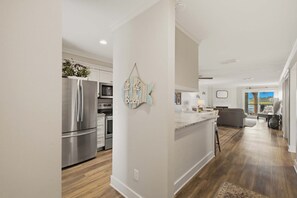 A modern kitchen with stainless steel appliances, a central island, and a view of the living area. - First-floor villa w/ magnificent river view & community pool/dock/tennis courts (Folly Beach)