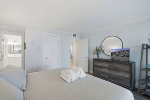 A hotel room with a bed, a dresser, a mirror, and a television.