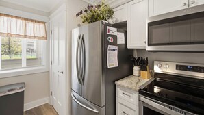 A modern kitchen with stainless steel appliances, a refrigerator, a microwave, and a stove. - First-floor villa w/ magnificent river view & community pool/dock/tennis courts (Folly Beach)