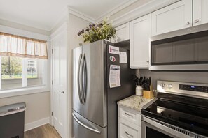 A modern kitchen with stainless steel appliances, a refrigerator, a microwave, and a stove. - First-floor villa w/ magnificent river view & community pool/dock/tennis courts (Folly Beach)