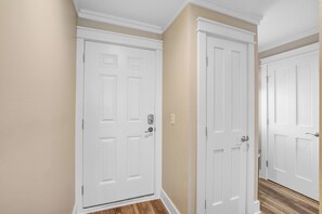 A hallway with two white doors, beige walls, and wooden flooring. - First-floor villa w/ magnificent river view & community pool/dock/tennis courts (Folly Beach)