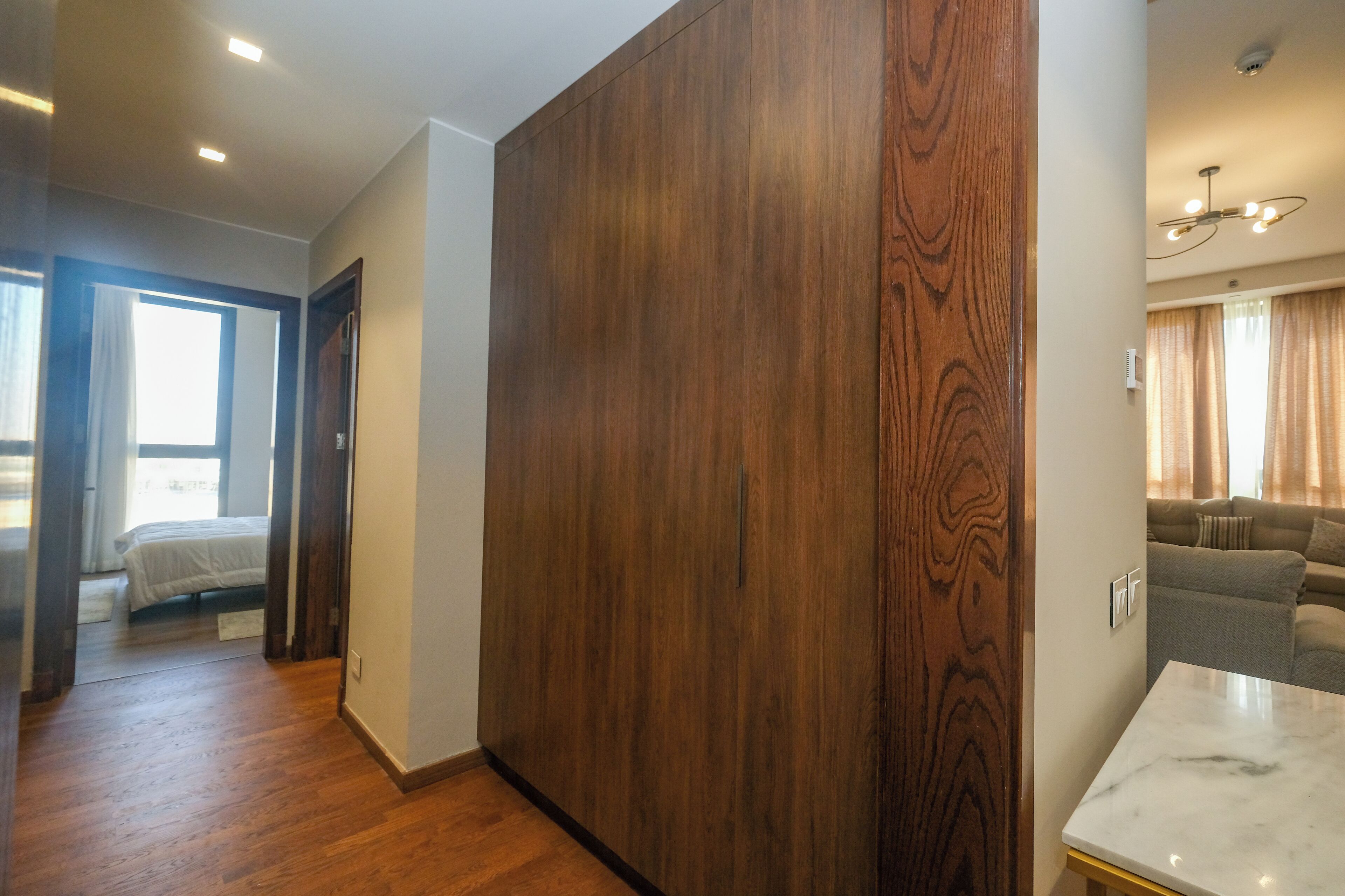 A modern room with a large wooden wardrobe, a marble table, and a sofa in the background.
