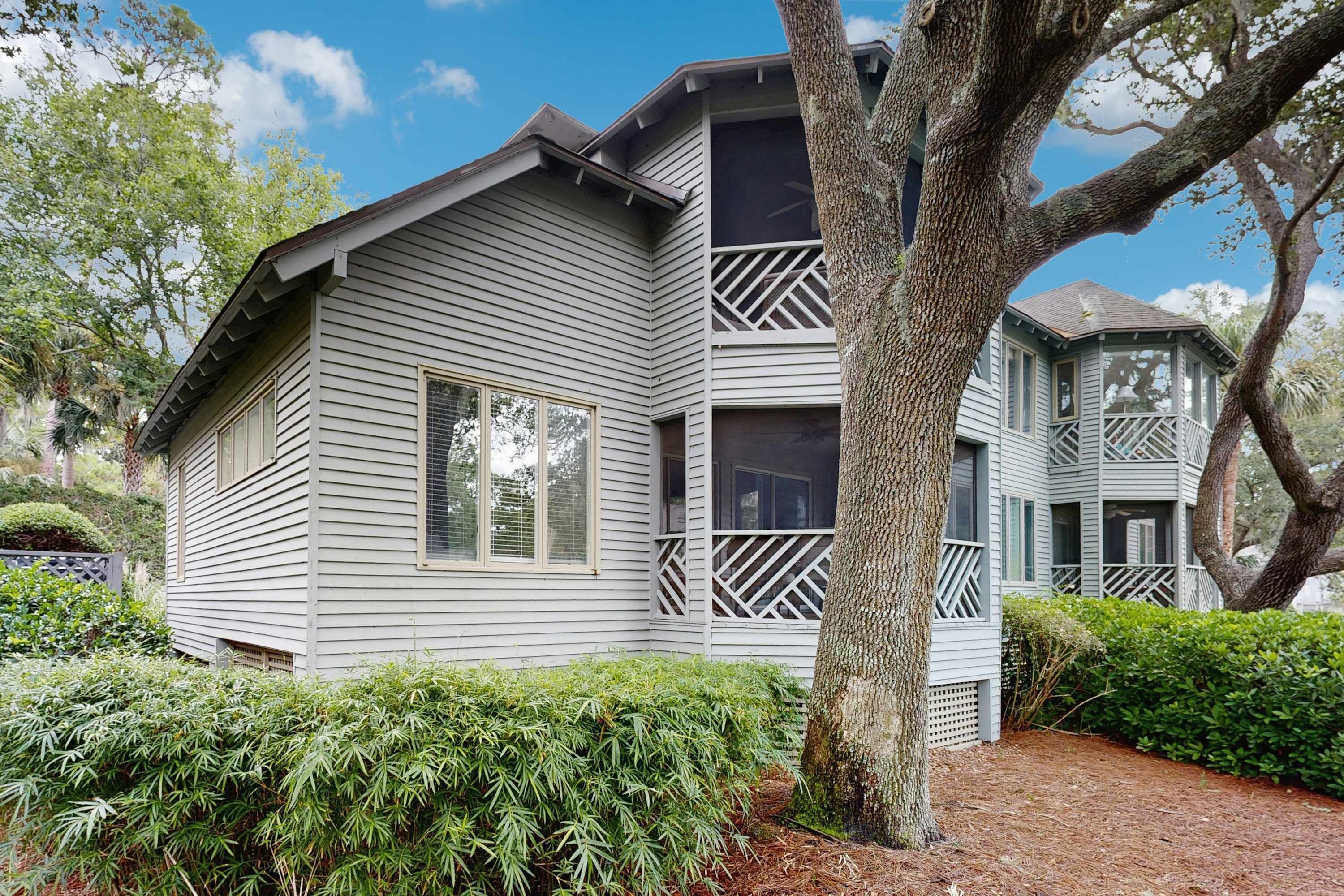 A two-story house with a balcony and a large tree in front.