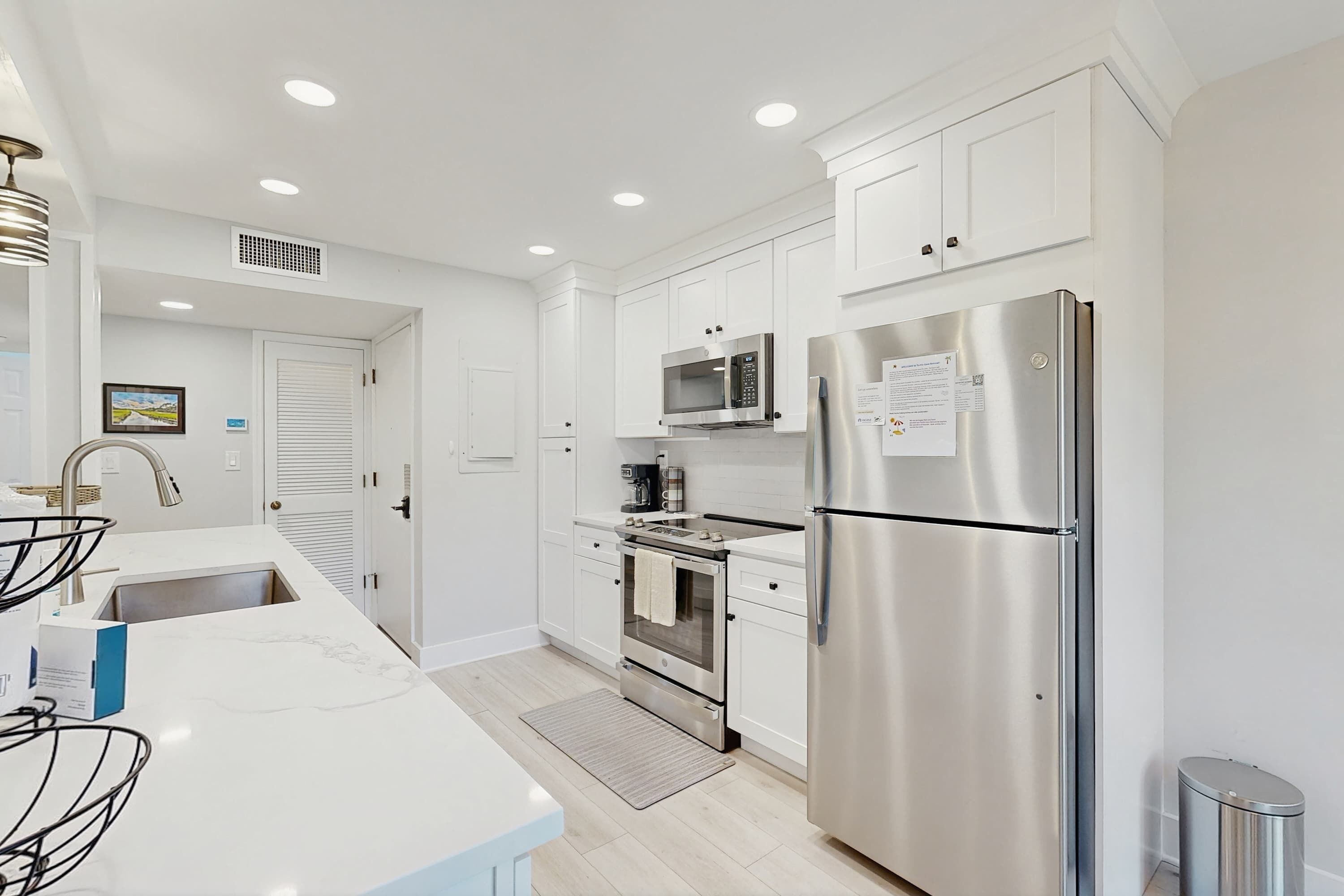 Una cocina moderna con armarios blancos, electrodomésticos de acero inoxidable y un microondas empotrado.