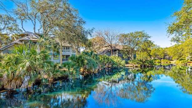 Una vista tranquila del lago con un reflejo claro, rodeado de abundante vegetación y arquitectura tradicional.