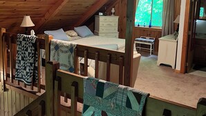 Une chambre mansardée chaleureuse, avec un plafond en pente, un lit, une commode et une fenêtre avec des rideaux.