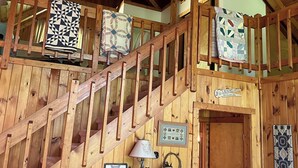 A wooden cabin interior with a staircase, a cabinet with a bear figurine, and a sign indicating a laundry service. - Hartford Hideaway! Soothing cabin in the Smokies. (Hartford)
