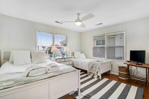 A bedroom with two beds, a ceiling fan, a TV, and a window with blinds. - Home with Free WiFi, a Full Kitchen, Five Decks, & Amazing Marsh Views (Folly Beach)