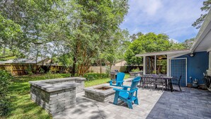 A backyard patio with stone seating, a fire pit, and outdoor furniture. - Stylish, Dog-Friendly, 30-Day Rental House w/Free WiFi, W/D, and Furnished Patio (Charleston)