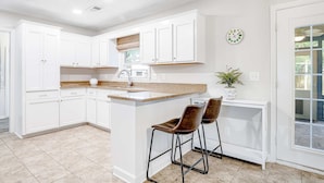 A kitchen with white cabinets, a granite countertop, and two bar stools. - Stylish, Dog-Friendly, 30-Day Rental House w/Free WiFi, W/D, and Furnished Patio (Charleston)