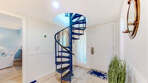 Un intérieur moderne avec un escalier en colimaçon bleu, une porte blanche et un tapis aux motifs bleus et blancs.