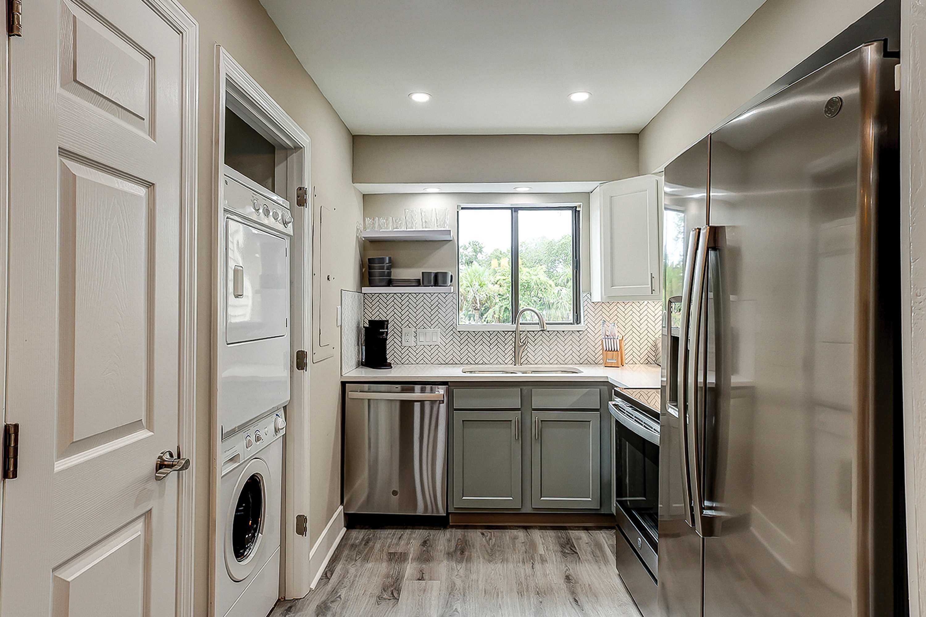 A modern kitchen with built-in appliances, a dishwasher, and a window providing natural light.