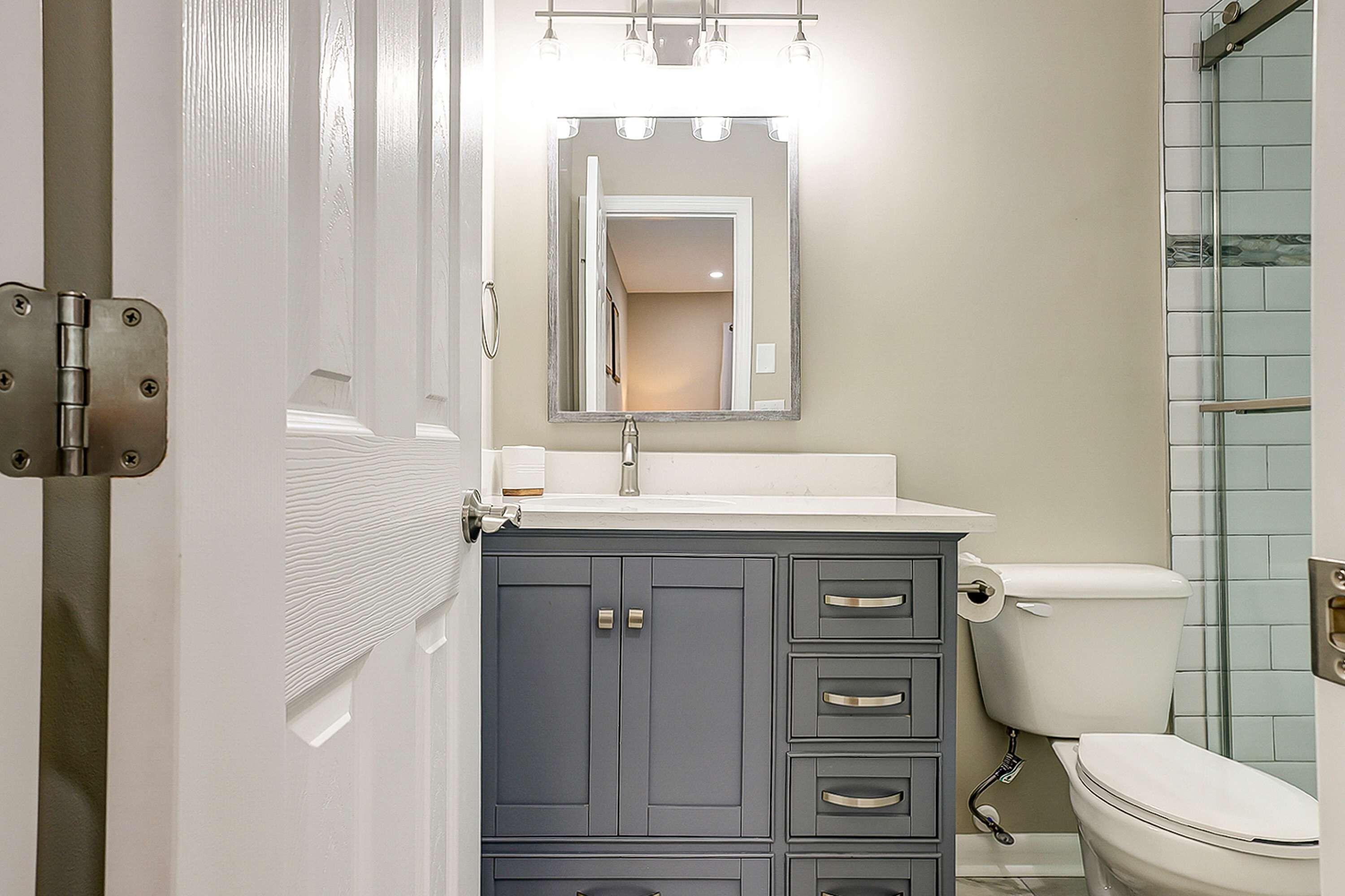 A bathroom with a white toilet, a sink with a mirror above it, and a cabinet with drawers.