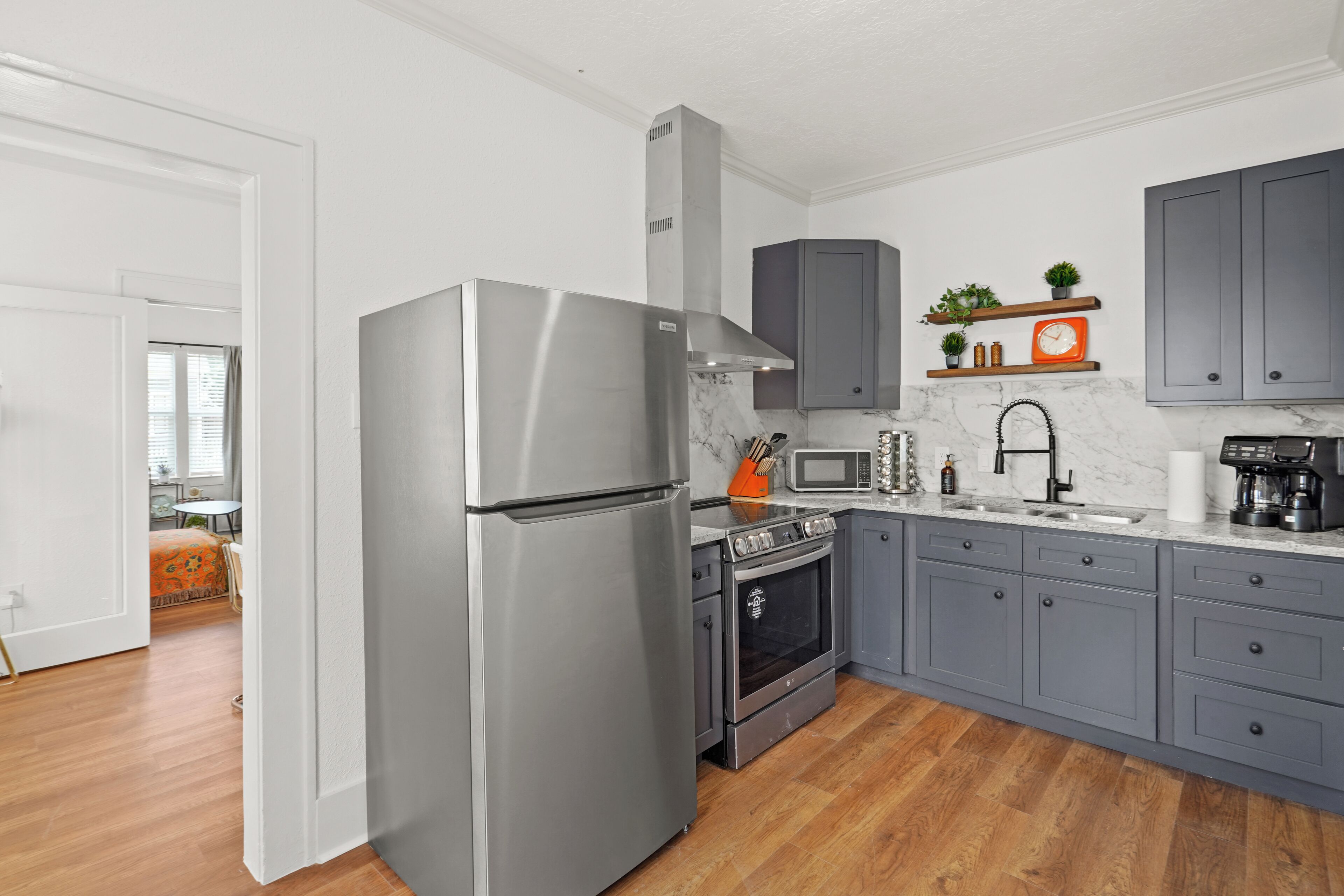 A modern kitchen with grey cabinets, a stainless steel refrigerator, an oven, and a microwave.