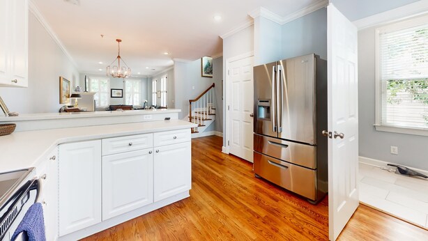 Una cocina moderna con armarios blancos, electrodomésticos de acero inoxidable y piso de madera.