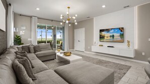 Una sala de estar moderna con un sofá modular, una mesa de centro y un televisor de pantalla plana montado en una pared blanca.