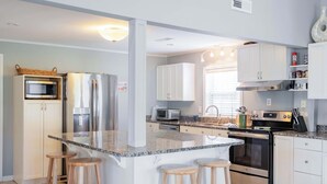 Una cocina moderna con una isla central, electrodomésticos de acero inoxidable y muebles blancos.