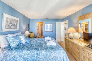 Une chambre à coucher avec un lit, une commode, un miroir et un tableau encadré accroché au mur.