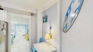 Una stanza con un tavolo bianco e sedie blu, una lampada e una sveglia a muro.