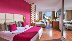 A hotel room with a large bed, a desk, and a chair. There is a window with curtains and a view of the outside. - regency hammamet (Hammamet)