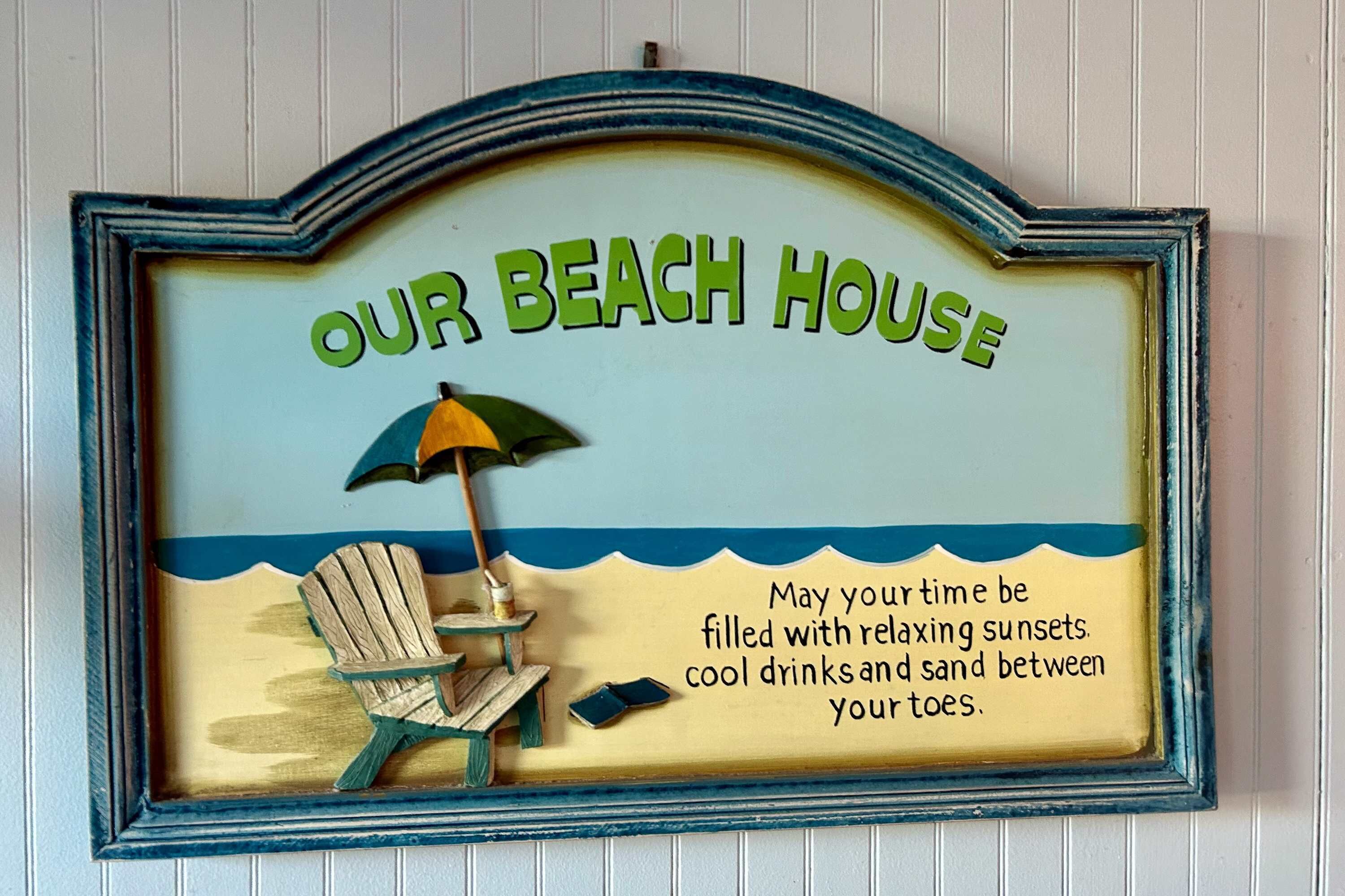 A decorative sign with the text "OUR BEACH HOUSE" and a beach scene illustration.