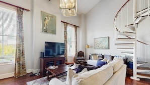 Una sala de estar con un sofá, una televisión, una mesa de centro de madera y una escalera.