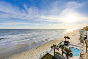 A beach view with a pool and palm trees. - Oceanfront villa with incredible views, balcony & 2 community pools (Folly Beach)