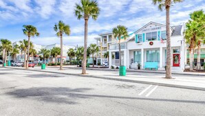 A street with palm trees, a white building with a sign reading "Papi's Taverna," and a red door. - Three-story ocean-view villa with pool, balcony, charcoal grill, & central AC (Isle of Palms)