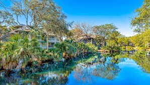 A serene lakeside view with a clear reflection, surrounded by lush greenery and traditional architecture. - Cozy Kiawah Island villa centrally located near local attractions (Kiawah Island)
