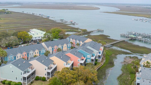 A coastal residential area with colorful houses, a marina, and a bridge connecting to the mainland. - Beachy, three-story villa w/ deck & shared pool - walk downtown & to the beach (Folly Beach)